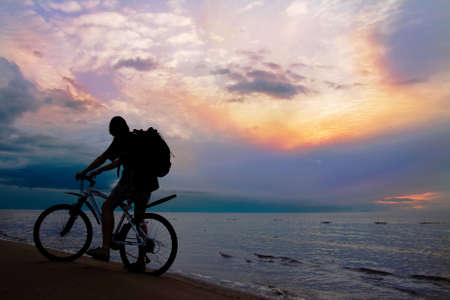 Mountain biker on beach and sunset, stormy skyの写真素材