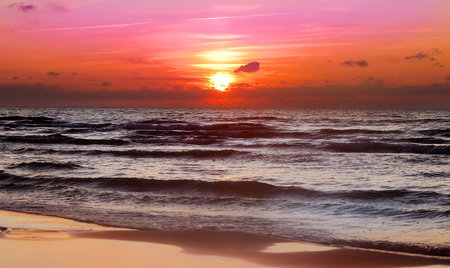 Beautiful sunset on the beach, autumn weather and wavesの写真素材