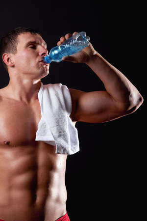 Portrait of muscular sportsman drinking waterの写真素材