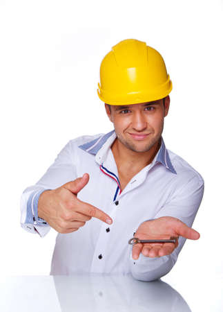 Portrait of smiling engineer posing in studio in helmet with keyの写真素材