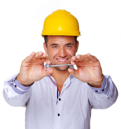 Portrait of smiling engineer posing in studio in helmet with keyの写真素材