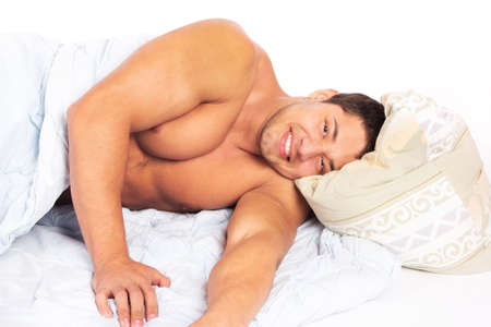 Portrait of a happy young man relaxing on bed at homeの写真素材