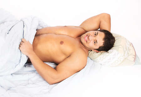 Portrait of a happy young man relaxing on bed at homeの写真素材