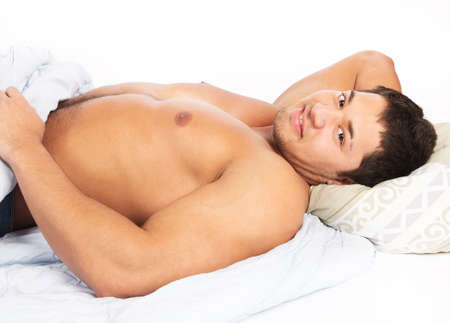 Portrait of a happy young man relaxing on bed at homeの写真素材