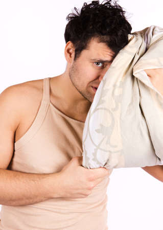 A tired looking man . He is holding a pillow の写真素材