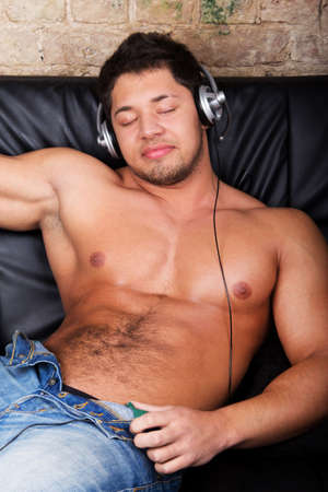 Portrait of a relaxed young guy enjoying music on headphone の写真素材