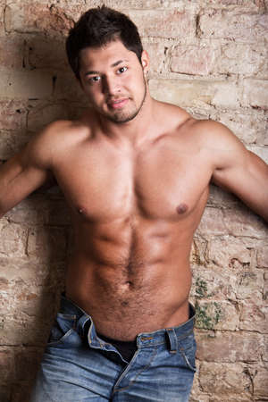 Portrait of a muscular man posing against old wallの写真素材