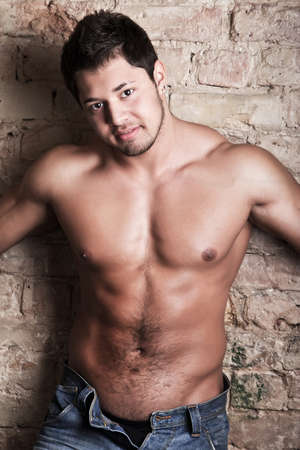 Portrait of a muscular man posing against old wallの写真素材