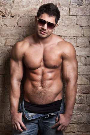 Portrait of a muscular man posing against old wallの写真素材