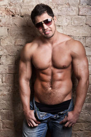 Portrait of a muscular man posing against old wallの写真素材
