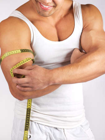 Muscular and tanned man is being measured の写真素材