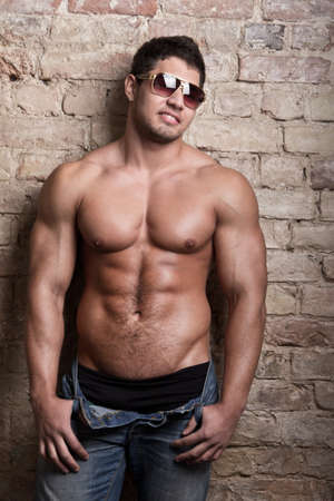 Portrait of a muscular man posing against old wall の写真素材