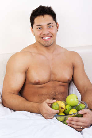 portrait of attractive young man with fruits in his bed の写真素材