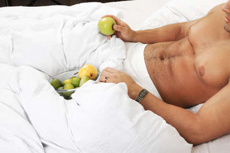 portrait of attractive young man with fruits in his bed  の写真素材