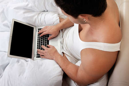 Young man using laptop at the bedtimeの写真素材