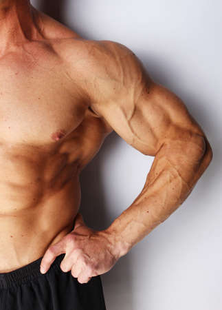 Closeup of body builders arm, isolated on grey