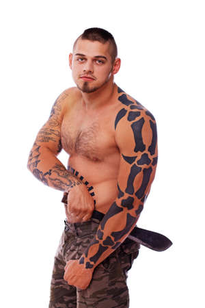 A man covered with tribal tattoos and armed with a knifeの写真素材