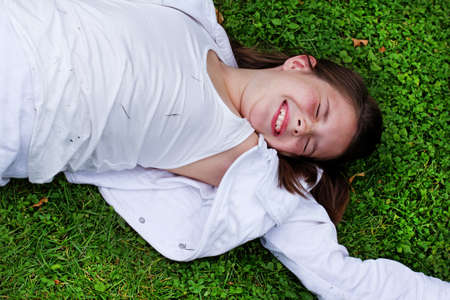 Portrait little girl posing on grass in sunny dayの写真素材