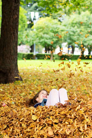 Portrait of little girl playing with leafs outsideの写真素材