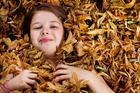 Portrait of little girl playing with leafs outsideの写真素材
