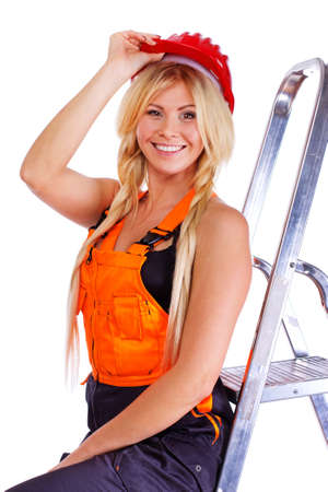 Portrait of sexy blonde worker posing in studio in red helmet near ladderの写真素材
