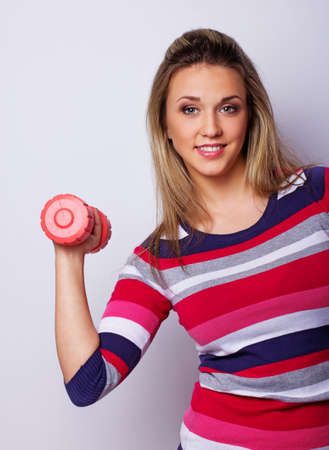 Portrait of sexy woman posing in studio with dumbbellsの写真素材