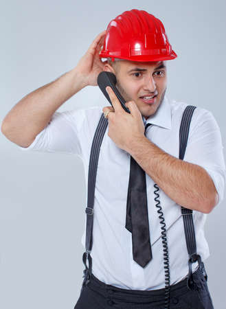 Portrait of sexy man posing in studio in red helmet with phoneの写真素材