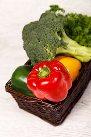 Vegetables in a basket on a light wooden table の写真素材