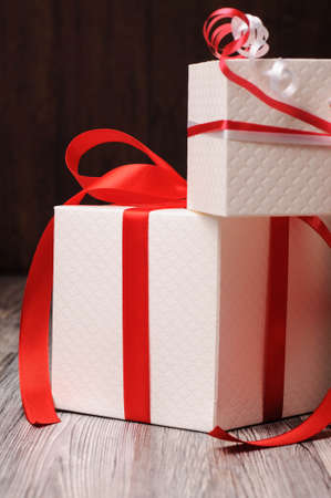 Two white gift boxes with red ribbonsの写真素材