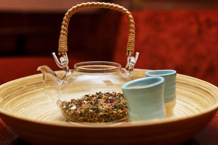 Glass teapot and two cups on a red wall の写真素材