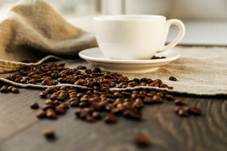 Cup of coffee on a cloth and wood with beans aroundの写真素材