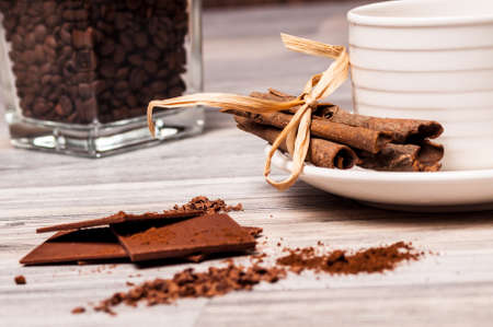 Coffee beans, chocolate, cinnamon and a white cup