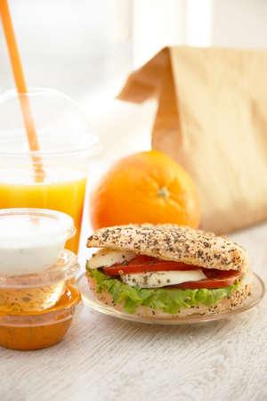 Takeaway orange juice and a sandwichの写真素材