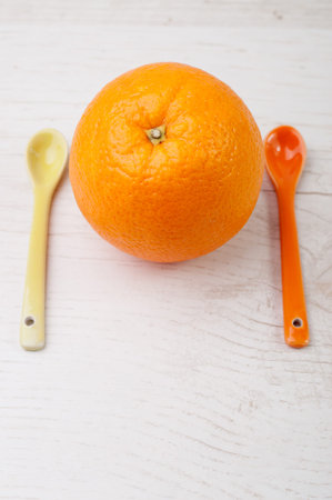 An orange inbetween two spoons
