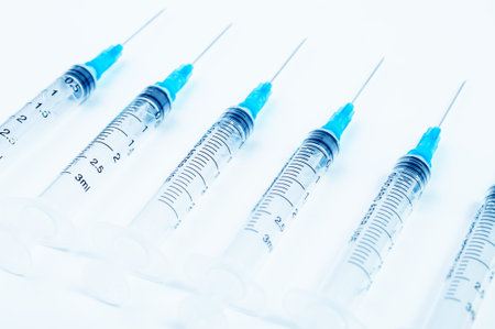 Six syringes on a white surface
