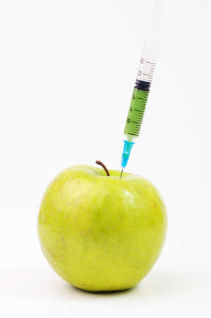 A green apple with green syringe in itの写真素材