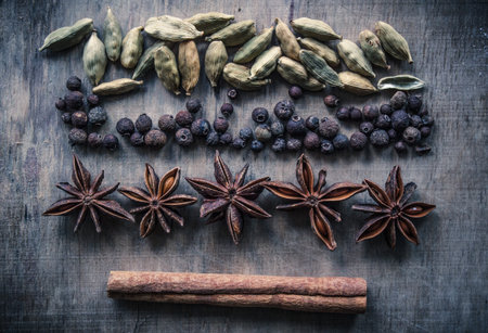 A cinnamon stick, star anise and black pepper on a wooden background