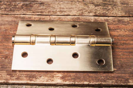 A metal door hinge on a wooden surfaceの写真素材