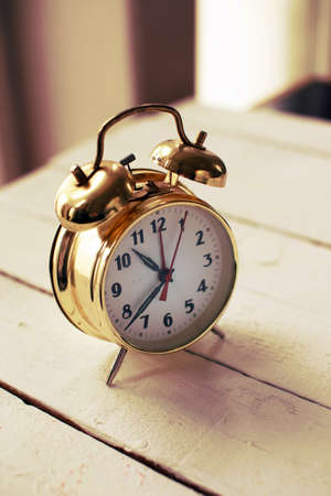 Image of gold alarm clock on the wooden tableの写真素材