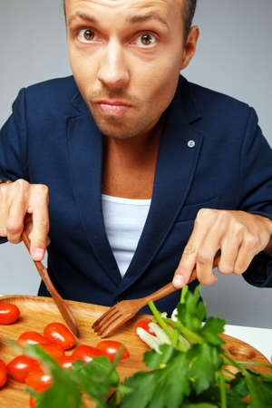 A man in a blue blazer eating tomatoesの写真素材