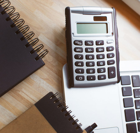 Two notebooks, a calculator and a laptop