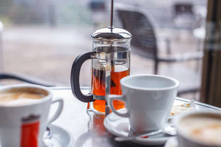 White cups with coffee and teapot with tee on the tableの写真素材