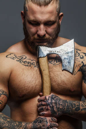 Huge brutal male with beard and tatooes holding axeの写真素材