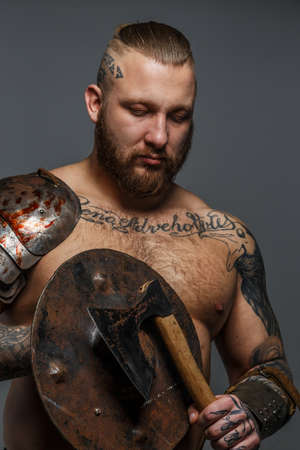 Strong brutal male with beard holding shield and axeの写真素材