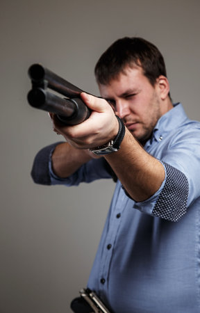 Serious man aims with shoot-gun