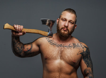 Huge brutal male with beard and tatooes holding axe