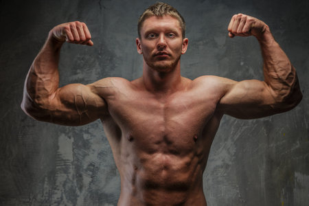 Muscular man  showing his great body on grey background.