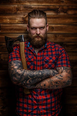 Huge brutal man with beard and tattooes holding axeの写真素材