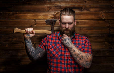 Huge brutal man with beard and tattooes holding axeの写真素材