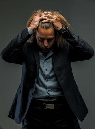 Portrait of handsome middle age long-haired stylish man in dark grey suit. Isolated on gray background.の写真素材